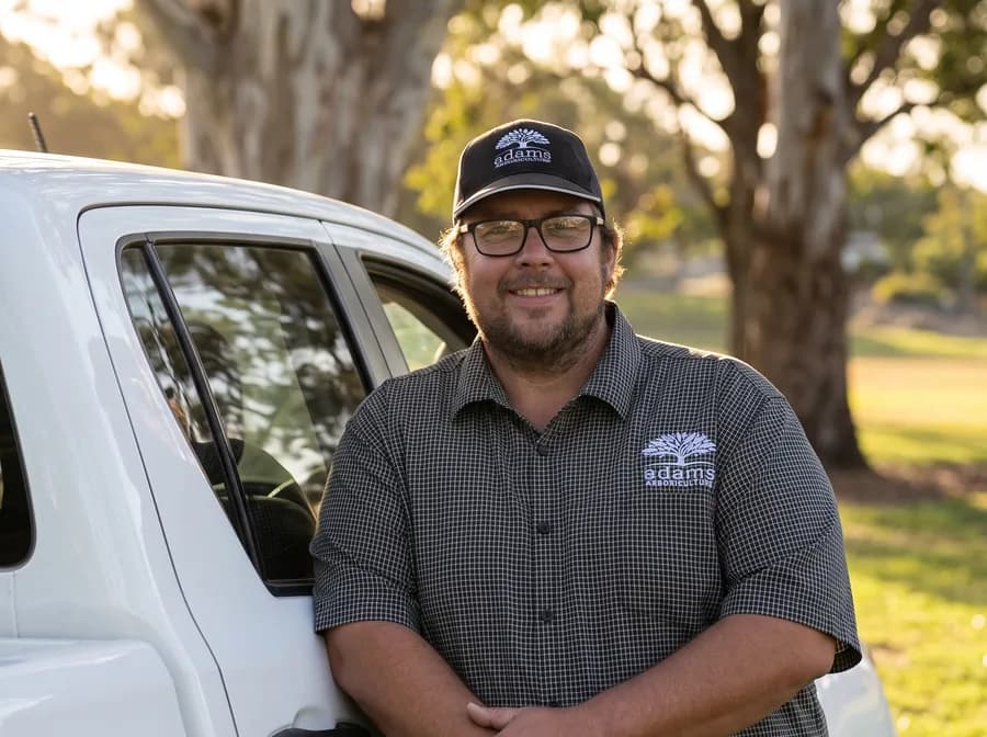 Adam De Regt, consulting arborist, standing beside his ute in parkland