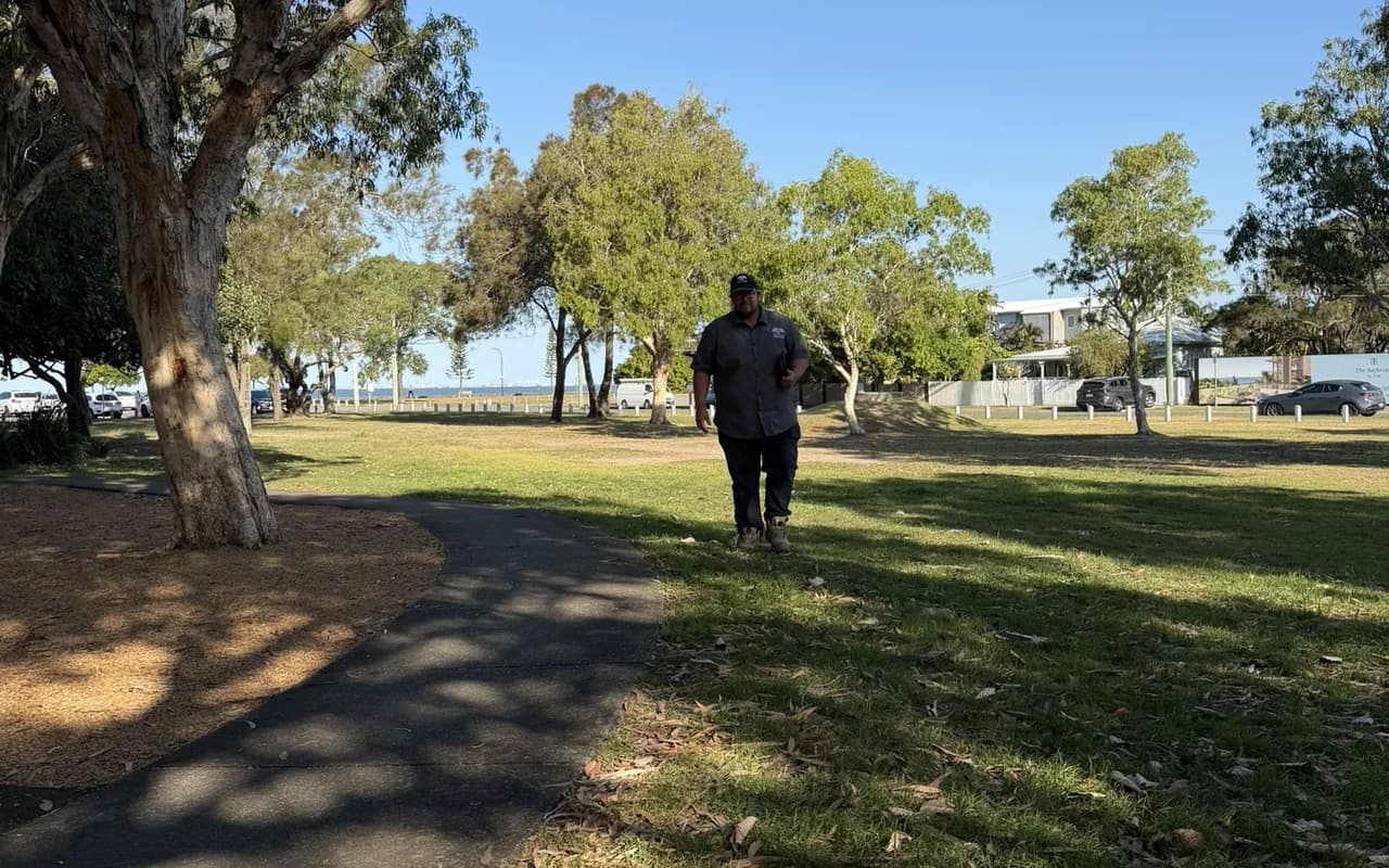 Adam De Regt walking a grassed site beneath mature trees