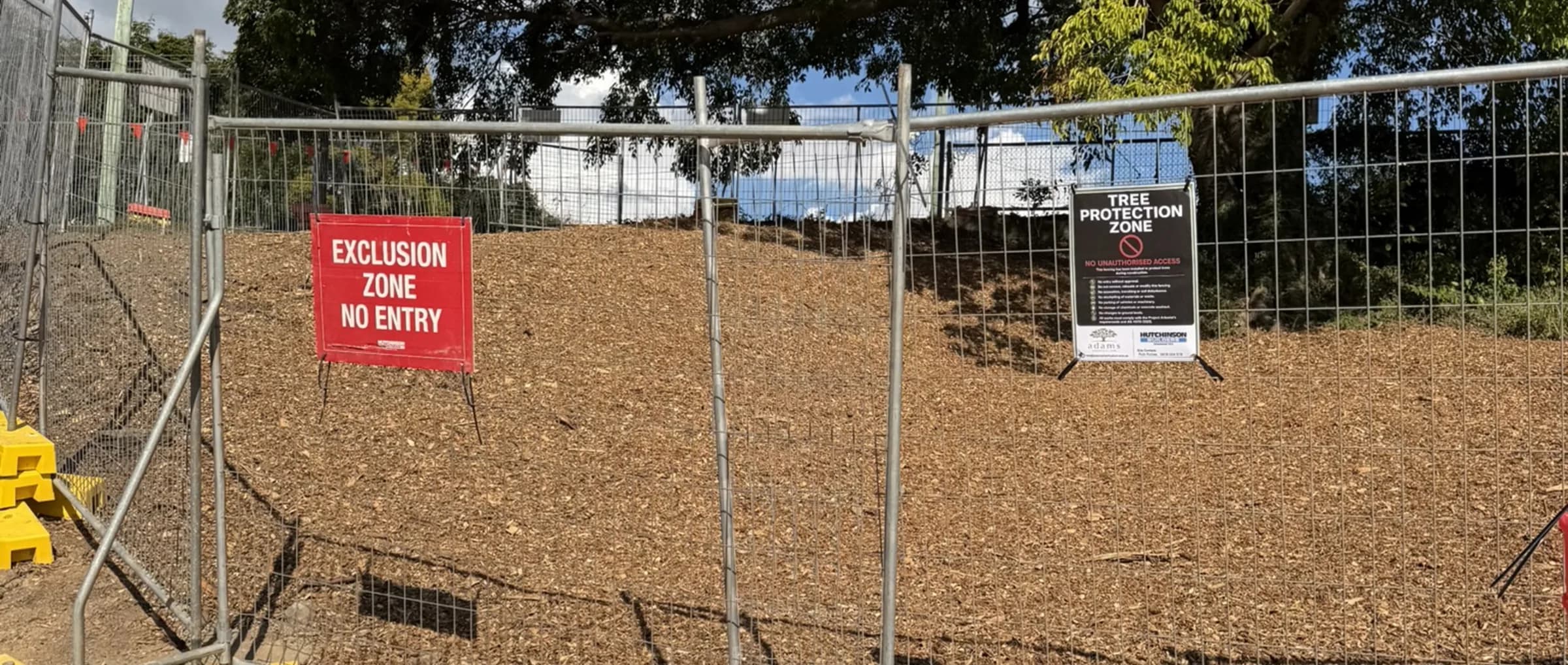 Temporary fencing and an exclusion zone sign enclosing the protected root zone of a retained tree on a construction site